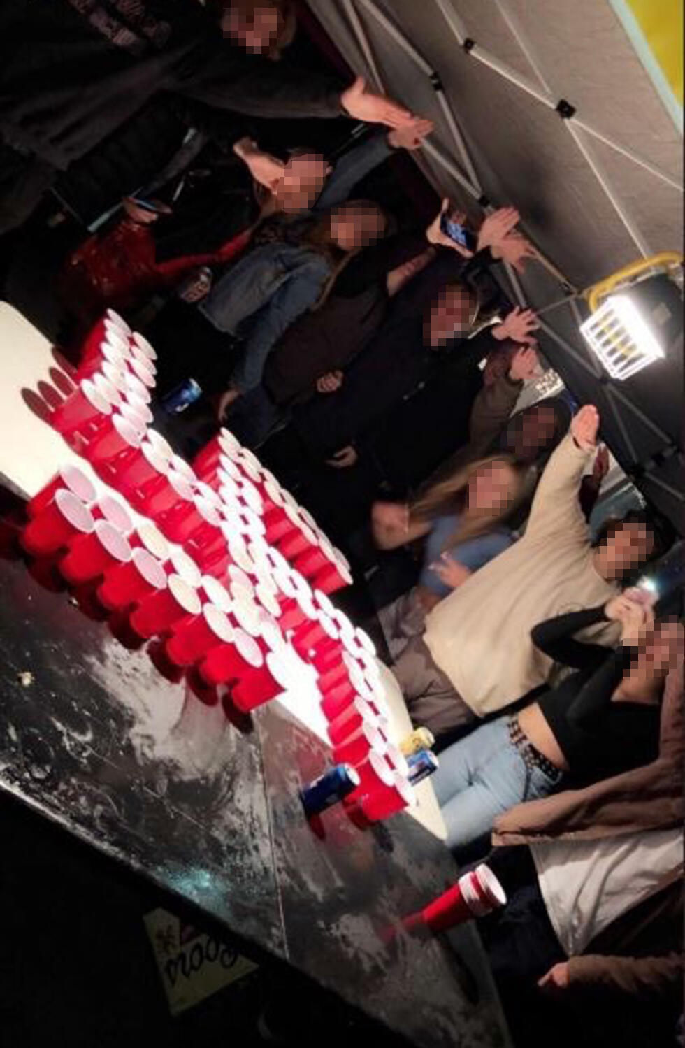 Orange County students playing beer pong with cups set up in a swastika formation 