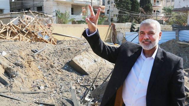 Ismail Haniyeh flashes a victory sign as he stands next to the rubble of his office building in Gaza City, March 27, 2019 