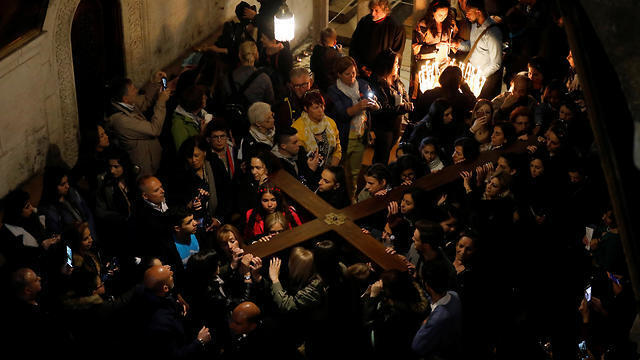 Worshippers carry a large wooden cross into the Church of the Holy Sepulchre on Good Friday (Photo: Reuters)