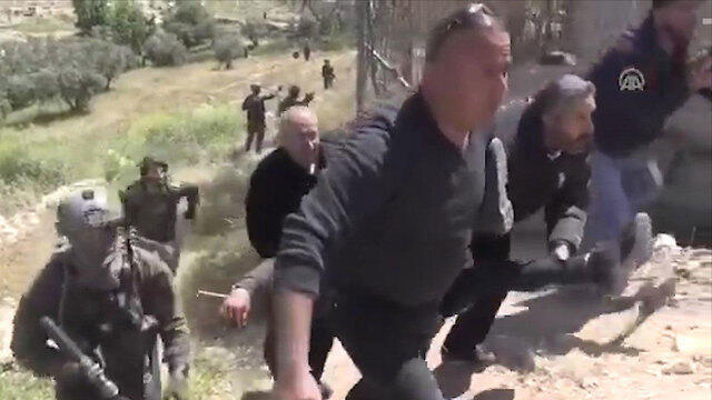 Раненного палестинца уносят местные жители 