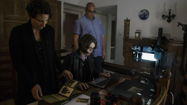 Yad Vashem officials Orit Noima, left, and Simmy Allen, watch archivist Lena Shternberg reproduce holocaust era photographs and documents
