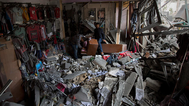 Gazans look at the damage to a shop hit by the IDF in Gaza City