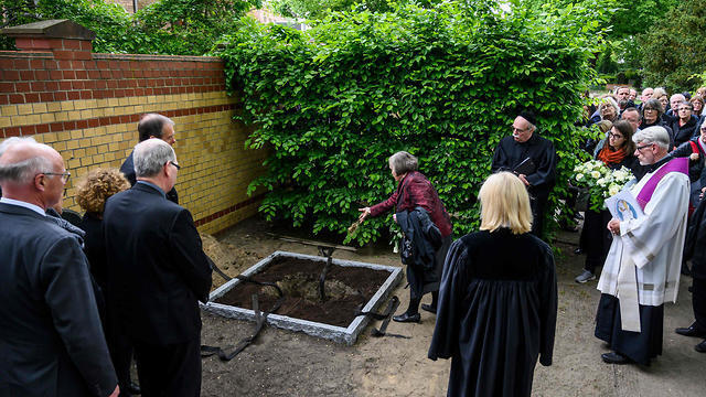 Saskia von Brockdorff throws soil on a box containing the remains of political prisoners executed by the Nazis  