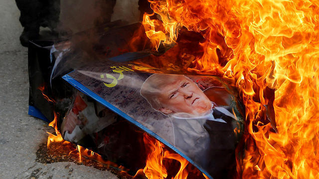 Protesters burn a photo of US President Trump
