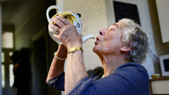 Judith Kerr drinks from a tea pot as she recreates a scene from her bestselling picture book 'The Tiger Who Came To Tea,' at her home in west London, Britain September 30, 2015
