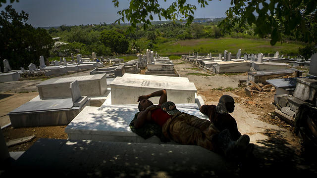 Workers repairing the Jewish cemetery take a break in the shade (Photo: AP) Workers repairing the Jewish cemetery take a break in the shade