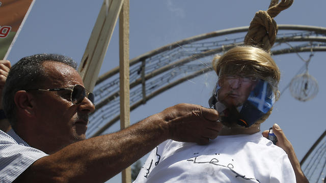 A Palestinian burns an effigy of the US President Donald Trump aduring a protest against the American-led Mideast peace conference