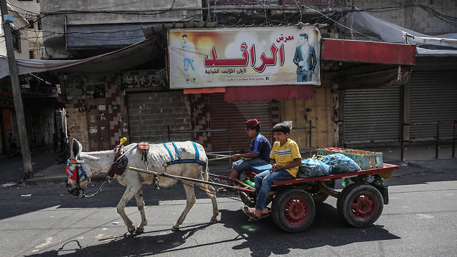 Palestinians vendor ride a cart and pass by shops closed during a general strike in Gaza City due to Bahrain summit