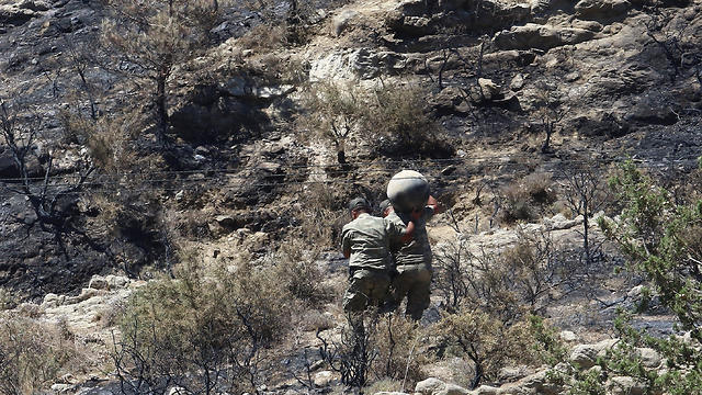 Military personnel carry debris on a slope where a missile struck, in Tashkent (also known as Vouno), in northern Cyprus, July 1, 2019