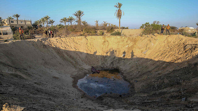 Palestinians inspect the damage after an Israeli strike