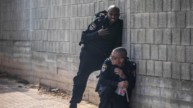 Israel Police officers take cover during a rocket strike on Sderot