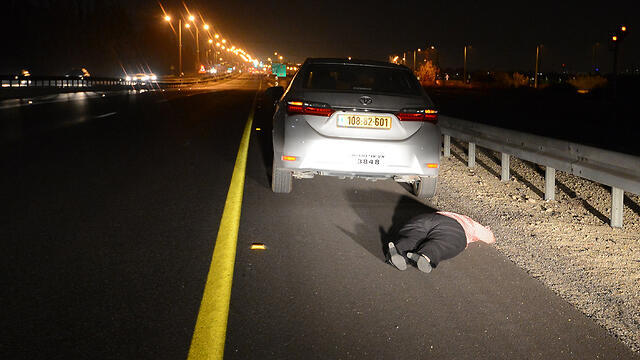 A man lies by the side of the road as rocket sirens sound in Ashdod