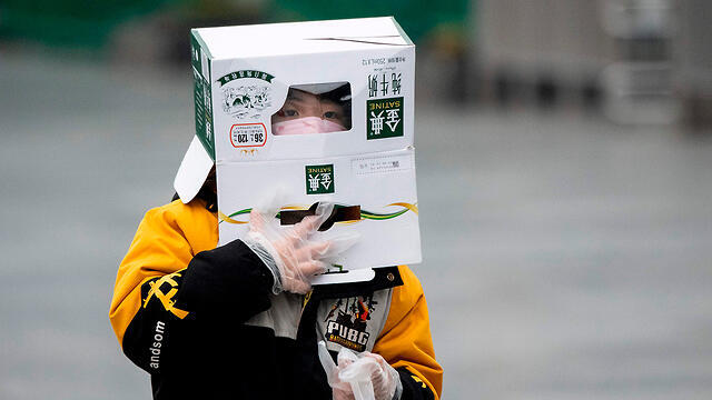 Житель Шанхая прикрывается картонной коробкой от коронавируса. Фото: AFP (צילום: AFP) Житель Шанхая прикрывается картонной коробкой от коронавируса. Фото: AFP