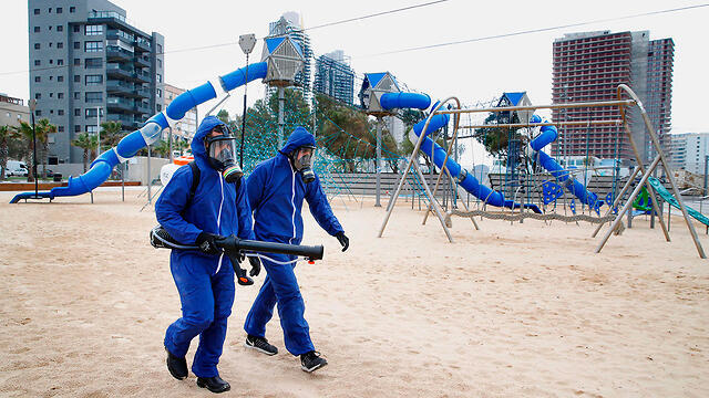 Дезинфекция детской площадки в Бат-Яме. Фото: AFP (צילום: AFP) Дезинфекция детской площадки в Бат-Яме. Фото: AFP