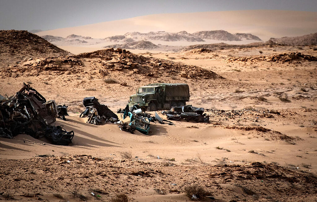 Moroccan army vehicle drives past car wreckages in Guerguerat located in the Western Sahara