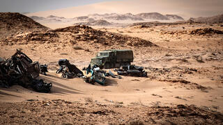 Moroccan army vehicle drives past car wreckages in Guerguerat located in the Western Sahara