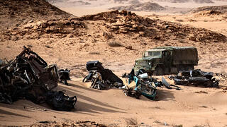 Moroccan army vehicle drives past car wreckages in Guerguerat located in the Western Sahara