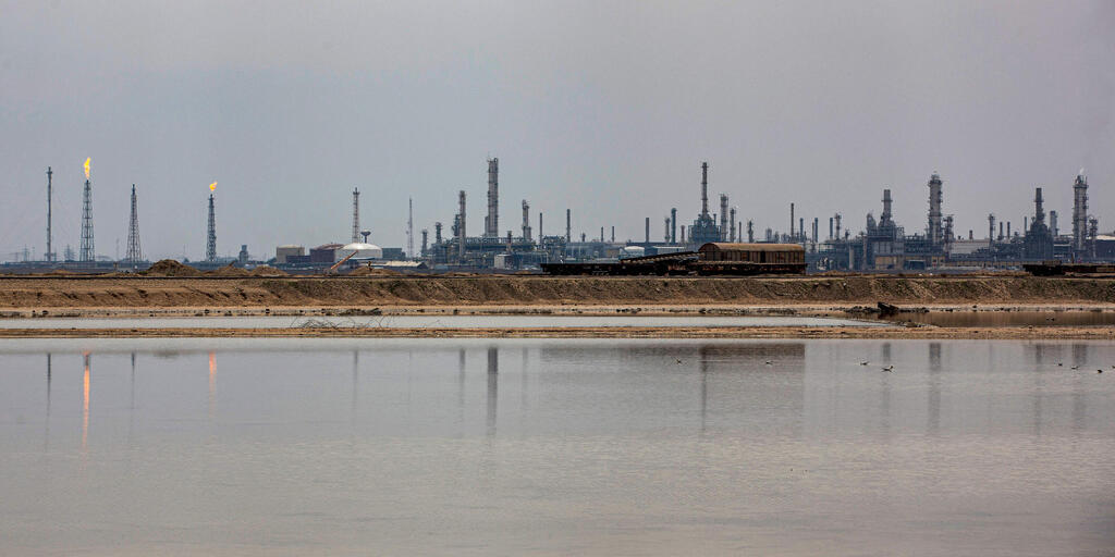 An oil refinery is seen across the water near Basra, Iraq (Photo: AFP) מתקן נפט ב בצרה עיראק