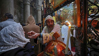 A Coptic priest gives the communion during mass on Easter Sunday at the Church of the Holy Sepulchre in Jerusalem on April 4, 2021 