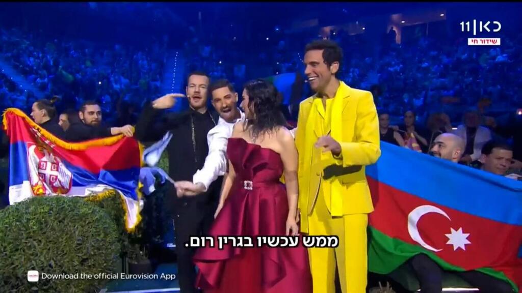 מיכאל בן דוד לצד מנחי האירוויזיון (צילום מסך) מיכאל בן דוד לצד מנחי האירוויזיון