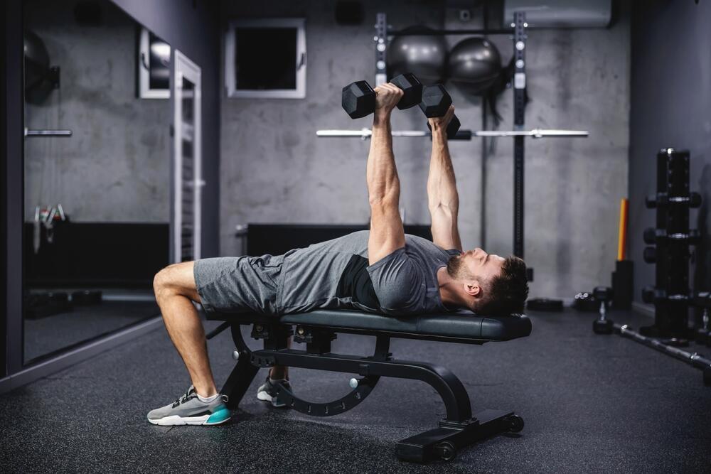 If fat is stored elsewhere, the abs may still be visible even without exceptionally low body fat (Photo: shutterstock) גבר צעיר מבצע אימון חזה באמצעות משקולות בחדר כושר