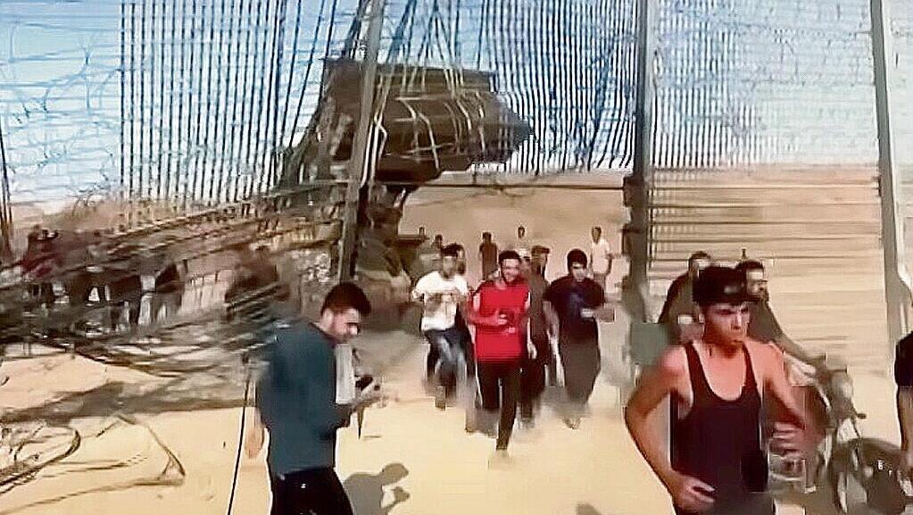 Gazans infiltrating into Israel through the breached border fence during the October 7 attack (Photo: Screengrab) פריצת הגדר בגבול עזה