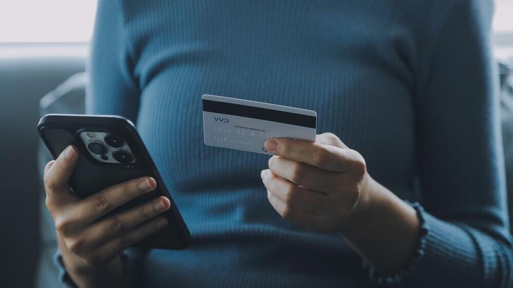 Photo: Shutterstock אישה עם טלפון וכרטיס אשראי