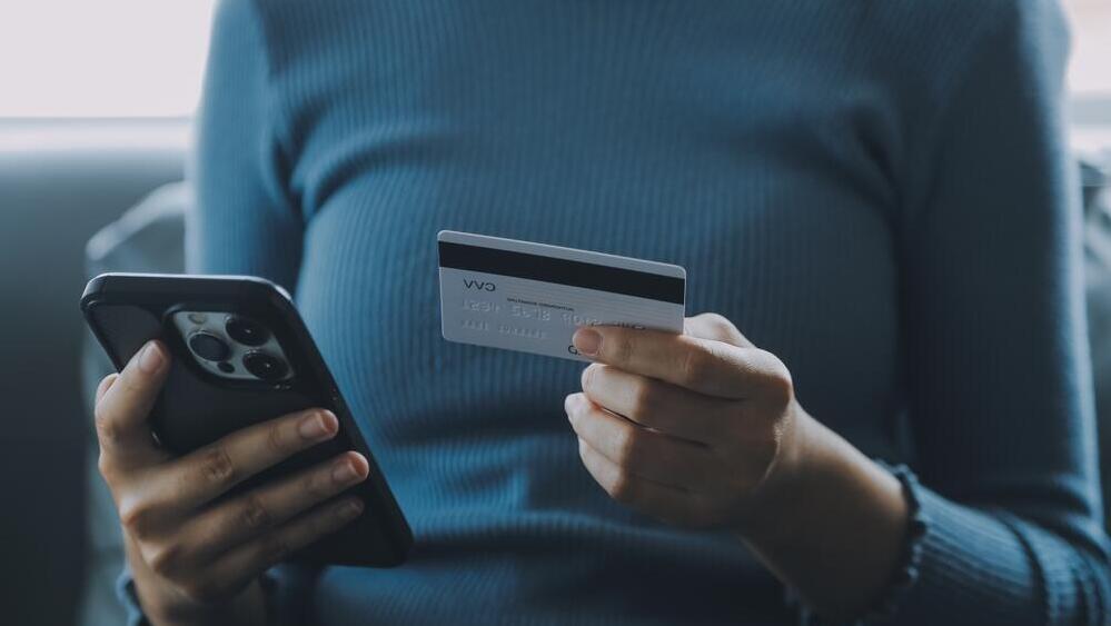 אישה עם טלפון וכרטיס אשראי