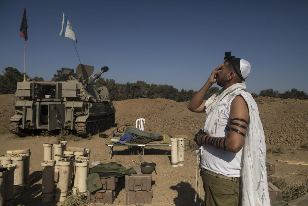 An IDF soldier prays near a self-propelled artillery unit positioned along the Gaza border, southern Israel, Nov. 6, 2023 (Photo: Amir Levy / Getty Images) חייל מתפלל ליד גבול רצועת עזה