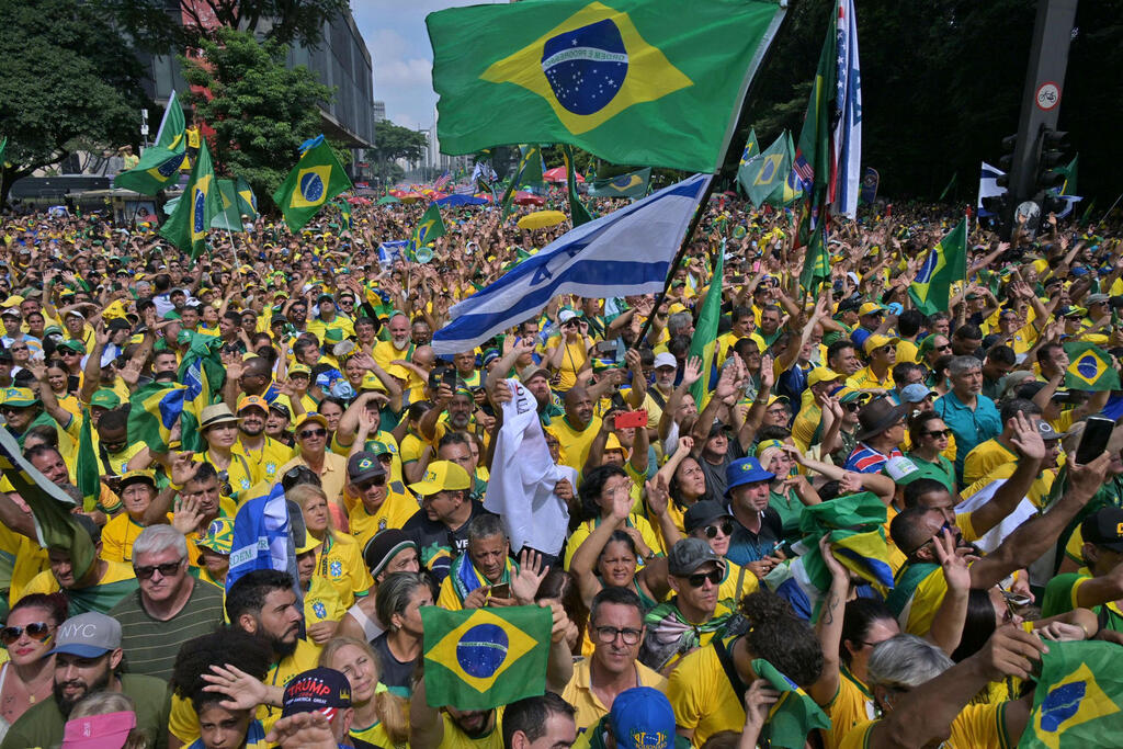 Supporters of Brazilian ex-president Jair Bolsonaro hoist Brazilian and Israeli flags during Sunday's São Paulo rally, February 2024 (Photo: NELSON ALMEIDA / AFP) עצרת תמיכה בבולסונרו בסאו פאולו, ברזיל
