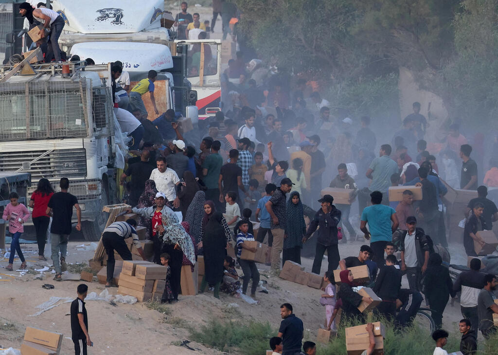 Palestinians climb onto trucks to grab aid that was delivered into Gaza through a U.S.-built pier 
