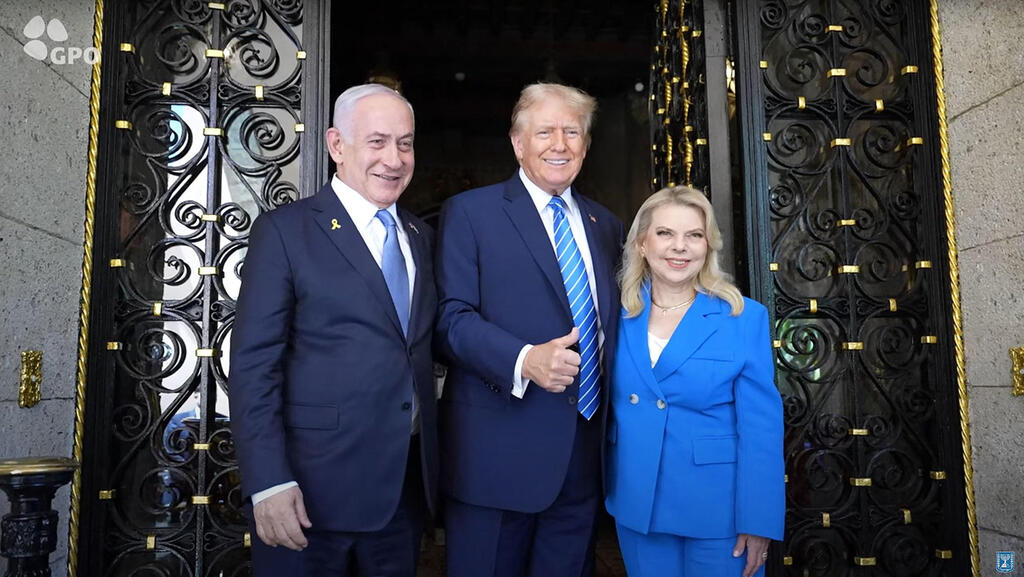 Benjamin and Sara Netanyahu with Donald Trump (Photo: ISRAELI GOVERNMENT PRESS OFFICE / AFP) בנימין ושרה נתניהו נפגשים עם דונלד טראמפ ותמונתו של אריאל ביבס