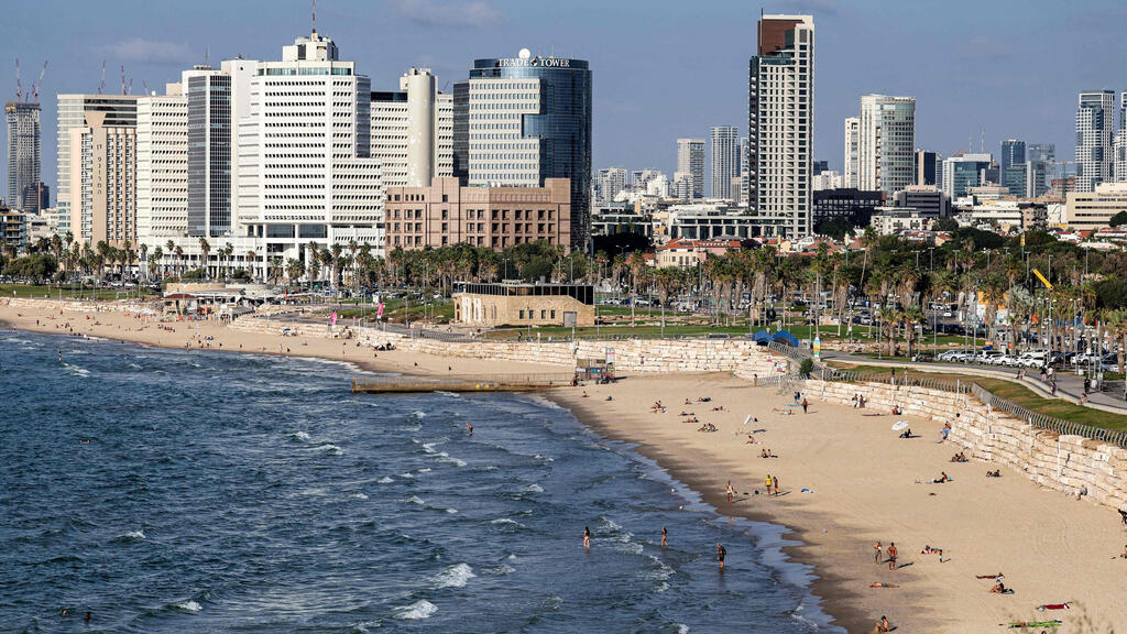 People sunbathe and splash in the Mediterranean waters along the Tel Aviv beach (Photo: Ahmad Gharabli/ AFP) אנשים משתזפים ומשתכשכים במימי הים התיכון לאורך חוף הים בתל אביב