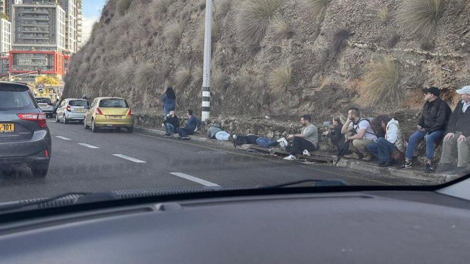 Civilians take cover on the side of the road in Herzlia during a missile attack (Photo: Elisah Ben Kimon) נשכבים על הריצפה באמצע הכביש באזור הרצליה בעקבות מטחים לשרון