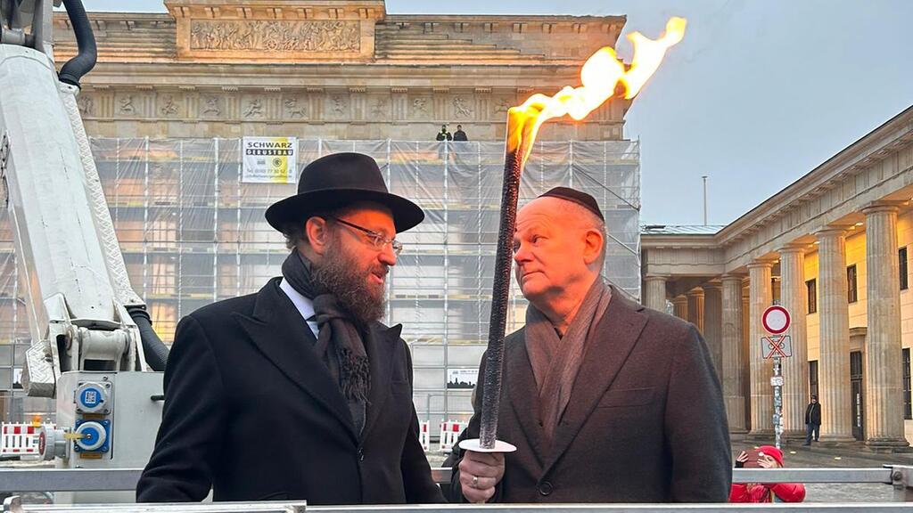 הרב טייכטל מדליק נר חנוכה בשנה שעברה עם הקנצלר הגרמני ב"שער הניצחון" בלב ברלין