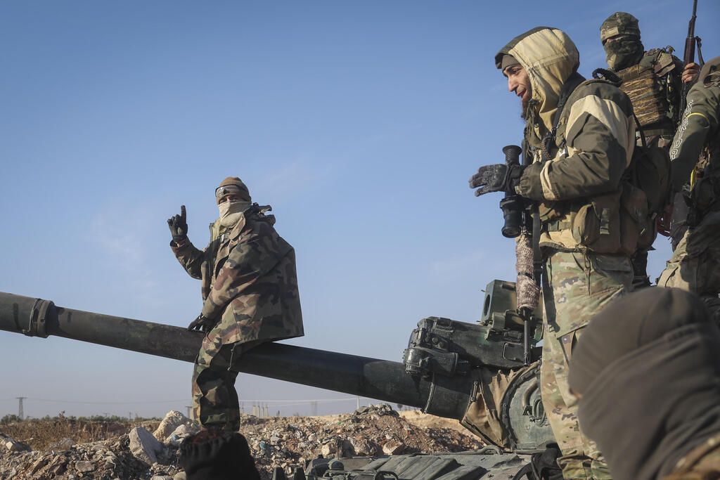 Syrian opposition fighters stand atop a seized military armored vehicle on the outskirts of Hama (Photo: Ghaith Alsayed / AP) מורדים סורים בפרברי העיר חמה סוריה