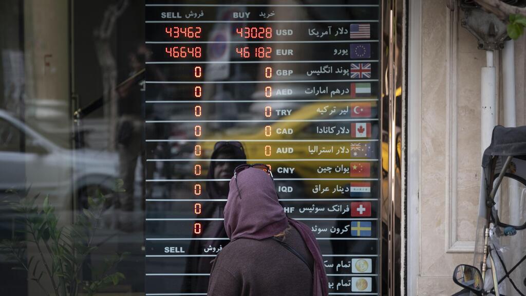 An Iranian woman in front ot an electronic foreign exchange board in Tehran (Photo: Morteza Nikoubazl, GettyImages) אישה איראנית מול לוח אלקטרוני של המרת מטבע בטהרן