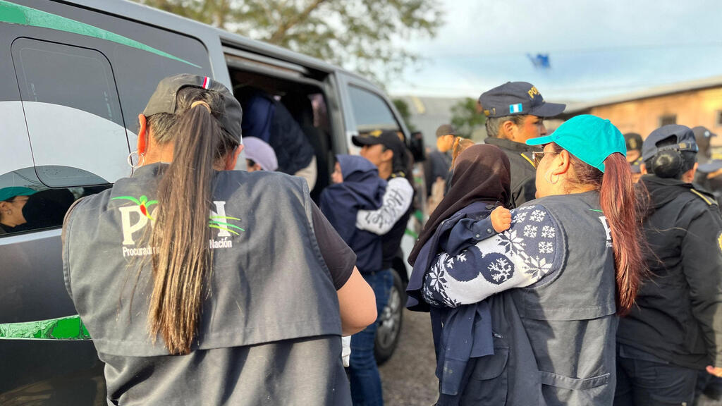 Rescued children from lev Tahor in Guatemala (Photo: Guatemalan Attorney General of the Nation's Office / AFP) שוטרות נושאות ילדים בידיהן לרכב המשטרתי