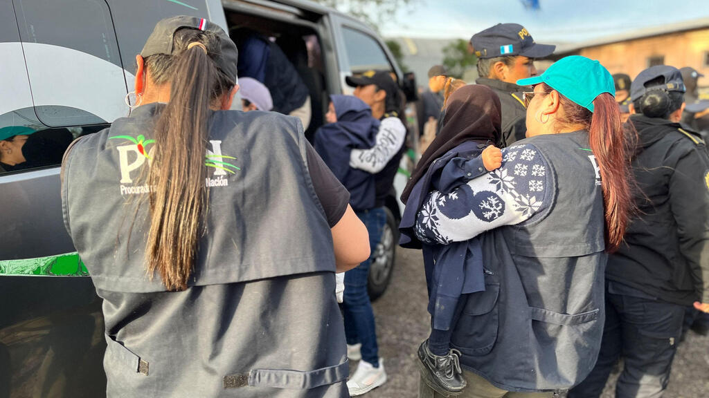 Guatemalan force during the rescue operation (Photo: Guatemalan Attorney General of the Nation's Office / AFP) שוטרות נושאות ילדים בידיהן לרכב המשטרתי