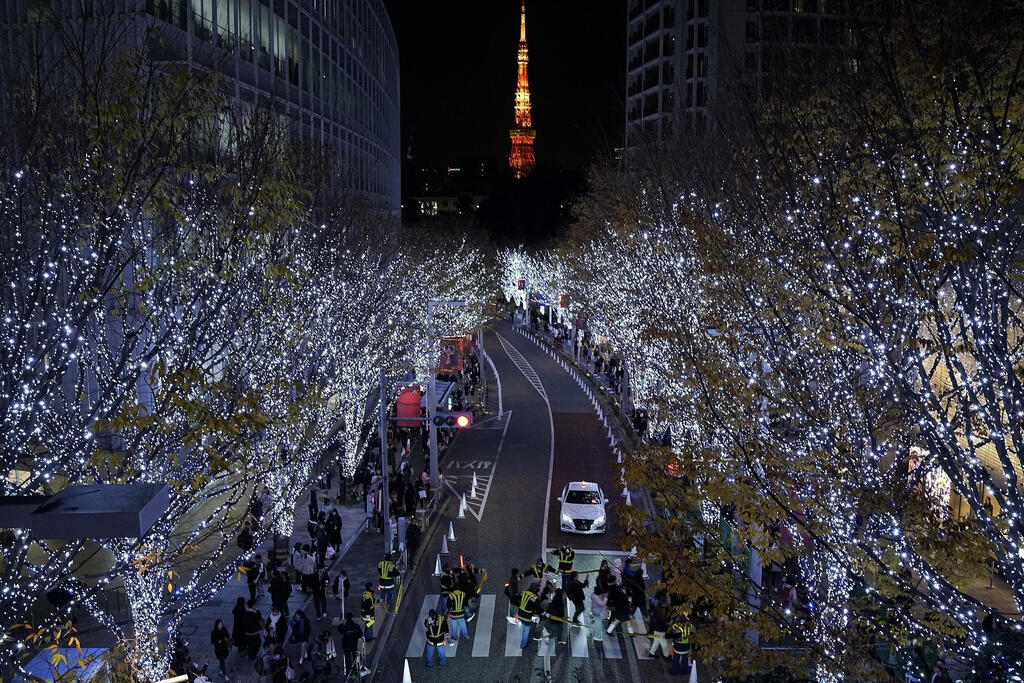 Tokyo: People stroll among the annual year-end lights in the Roppongi area (Photo: Eugene Hoshiko/AP) טוקיו: אנשים מטיילים בין אורות סוף השנה השנתיים באזור רופונגי