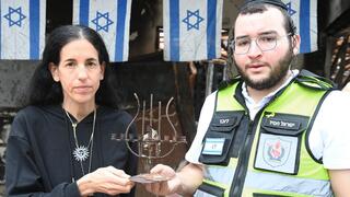 בתה של שפרה ז"ל, דורית נוי, עם ישראל חסיד איש זק"א מחזיקים את החנוכייה