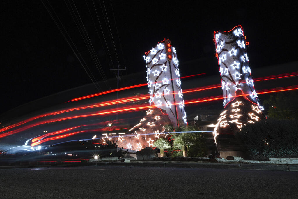 A pair of 12-meter-tall cowboy boots adorned with lights for the holidays (Photo: Eric Gay/AP) זוג מגפי בוקרים בגובה של כ-12 מטר שקושטו באורות לכבוד החגים