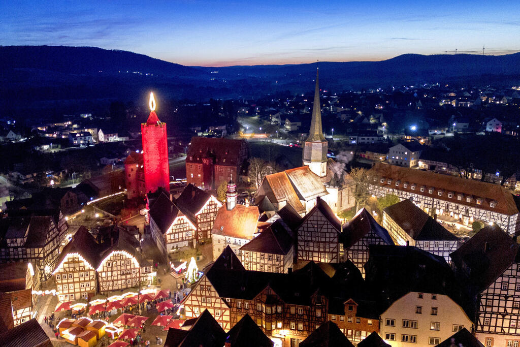 A 42-meter-tall candle, actually an illuminated medieval tower, glows in the historic center of Schlitz, Germany (Photo: Michael Probst/AP) נר בגובה 42 מטר, שהוא למעשה מגדל מימי הביניים מואר, זוהר במרכז העיר ההיסטורית של שליץ, גרמניה