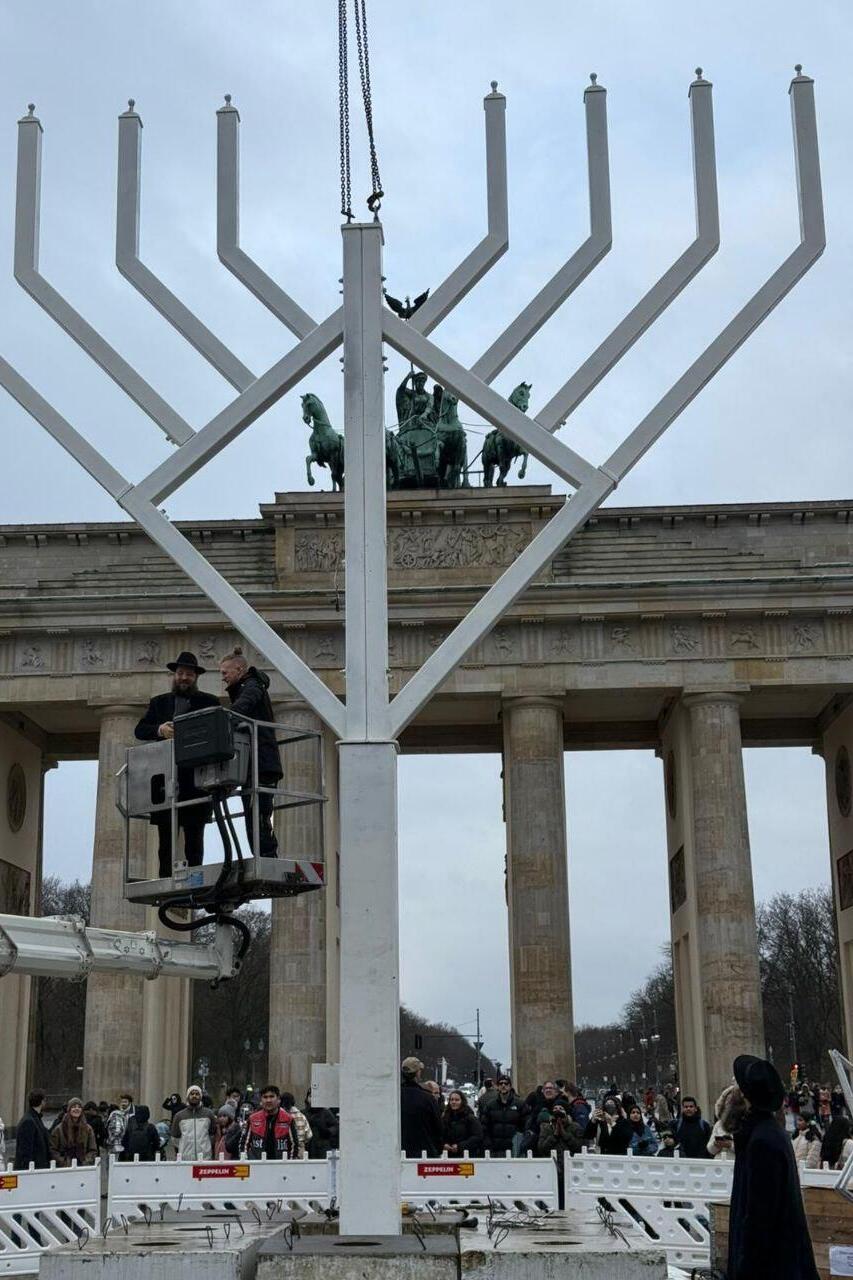 תיירים וצלמי תקשורת צופים ומתעדים את הצבת החנוכייה למרגלות שער בנדרבורג בברלין