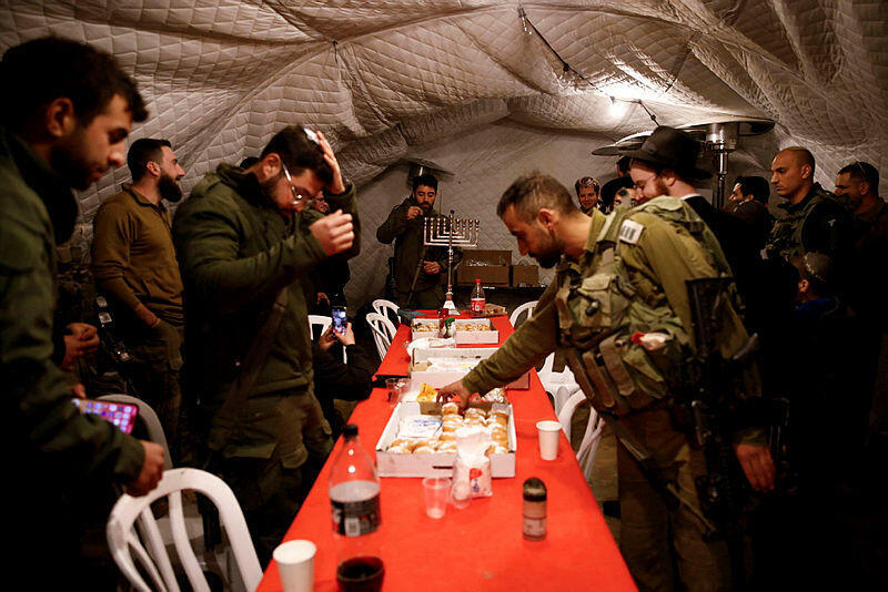 Israeli soldiers gather to celebrate the first day of Hanukkah, near the Israeli-Lebanon border