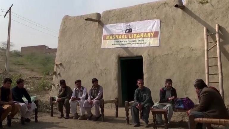 Villagers sit outside Mashaal Library