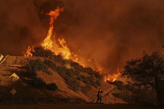 A firefighter sets up a hose while fighting the Palisades Fire in Mandeville Canyon 