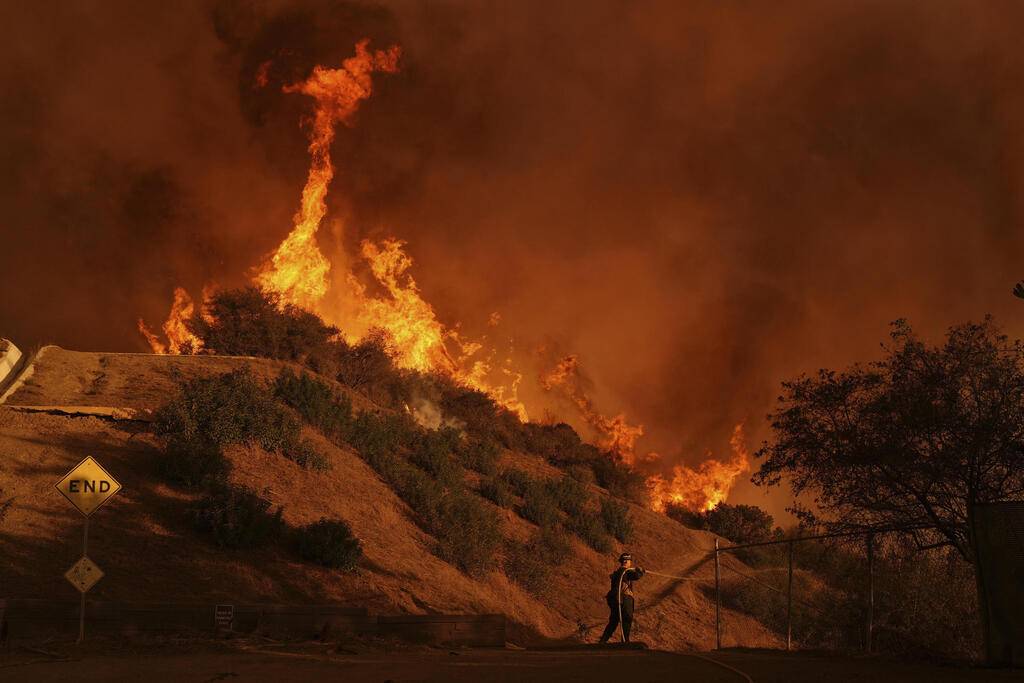 A firefighter sets up a hose while fighting the Palisades Fire in Mandeville Canyon 