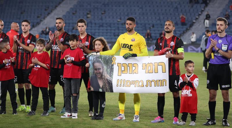 Hapoel Haifa players holding a banner saying 'Romi Gonen returns alive' (Photo: Radad Jabra) Hapoel Haifa players holding a banner saying 'Romi Gonen returns alive'