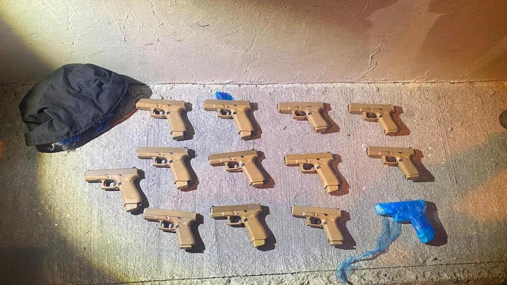 The 13 Glock pistols thrown from onto the highway by the suspected criminal during a police chase (Photo: Israel polices spokesperson) אמצעי הלחימה שנתפסו על ידי המשטרה במהלך מעצר חשוד בכביש 6 סמוך ליקנעם
